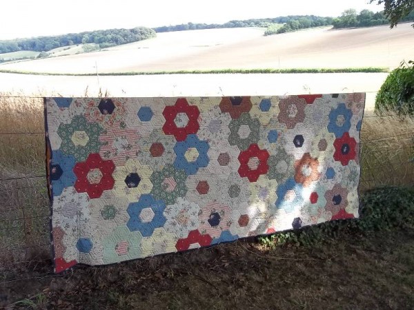 Grandmother's flower garden quilt - used as a curtain but having a brief airing in the garden 