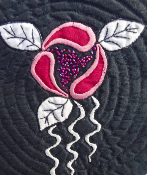 Hand embroidered and beaded rose appliquéd on to black silk.