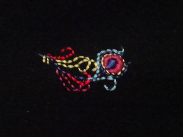 Brightly embroidered feather on black cashmere (hand embroidered by Mary Addison)