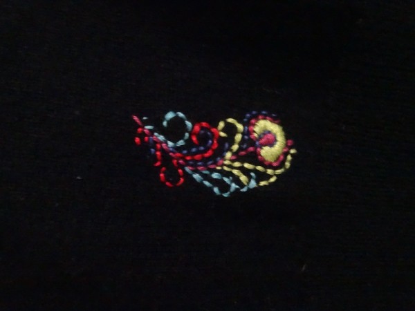 Brightly embroidered feather on black cashmere (hand embroidered by Mary Addison)